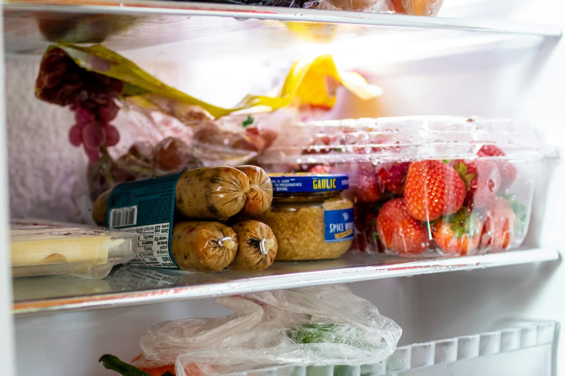 Open refrigerator stocked with groceries, fresh produce, and beverages